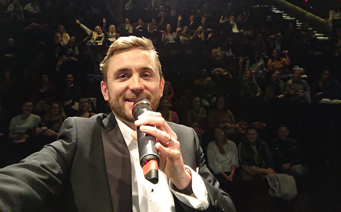 Kevin Durham on the mic with a full auditorium behind him