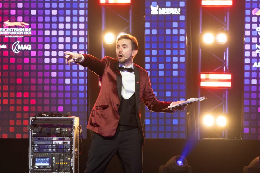 Kevin Durham on stage in front of an LED wall, calling the next round