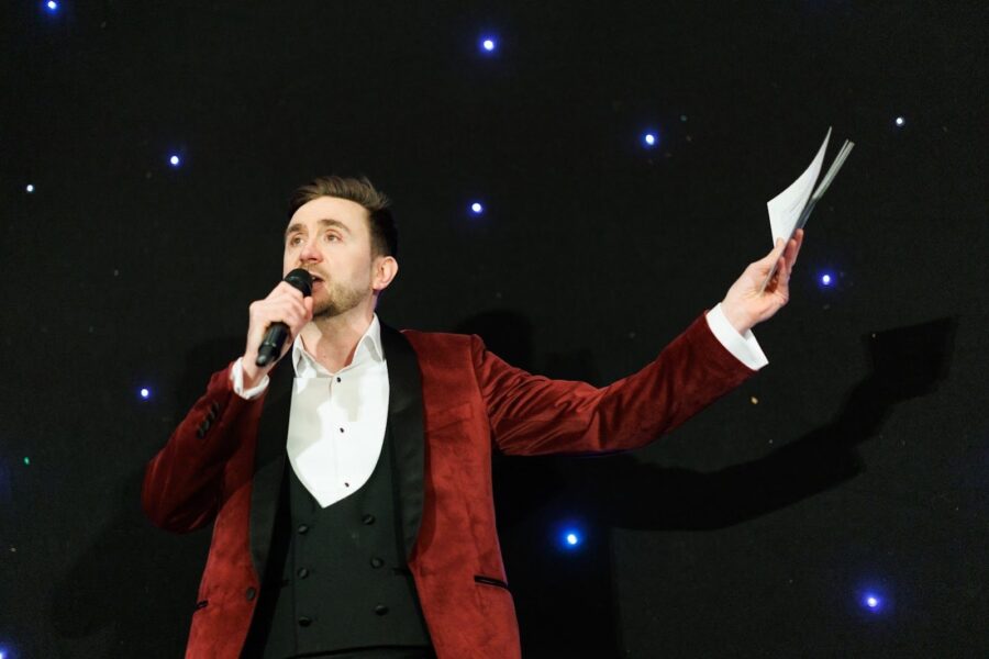 Kevin Durham on stage under the lights with the running order in hand